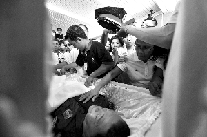 28日，兇手門多薩身著警服躺在棺木里。