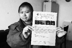 女孩眼含淚水向記者出示自己母親的診斷報(bào)告，希望好心人可以幫幫她的母親。　　攝影 李自強(qiáng)