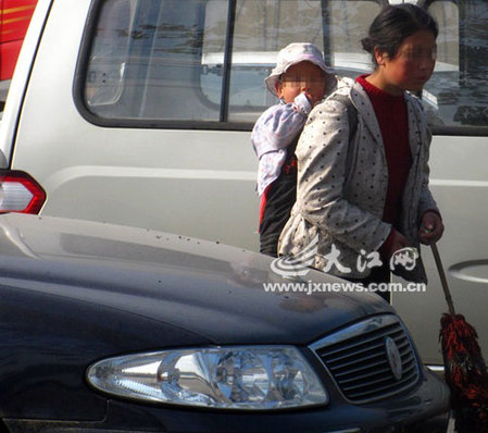 女子背小孩車(chē)流中乞討市民相勸被罵“關(guān)你屁事”