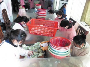 點鈔員們在低頭緊張地工作，她們每人每天都需要點鈔25箱1萬元以上。 陳暄 攝