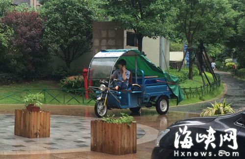 這名快遞哥騎行在小區通道內，一邊接打手機，一邊還把腳架在車前欄桿上