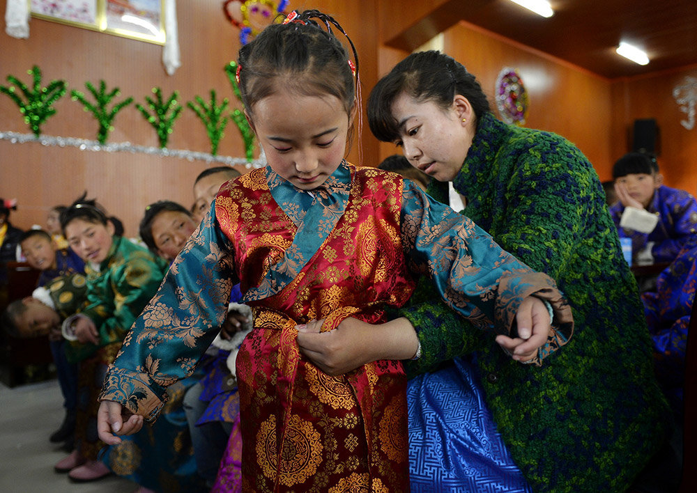 2月27日，在西藏自治區(qū)兒童福利院，來自拉薩市尼木縣的“愛心媽媽”德慶旺姆（右）在為來自那曲地區(qū)的嘎瑪曲宗換上節(jié)日盛裝。